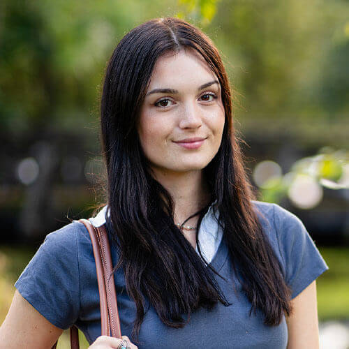 Eleanor, female student smiling to camera in campus grounds