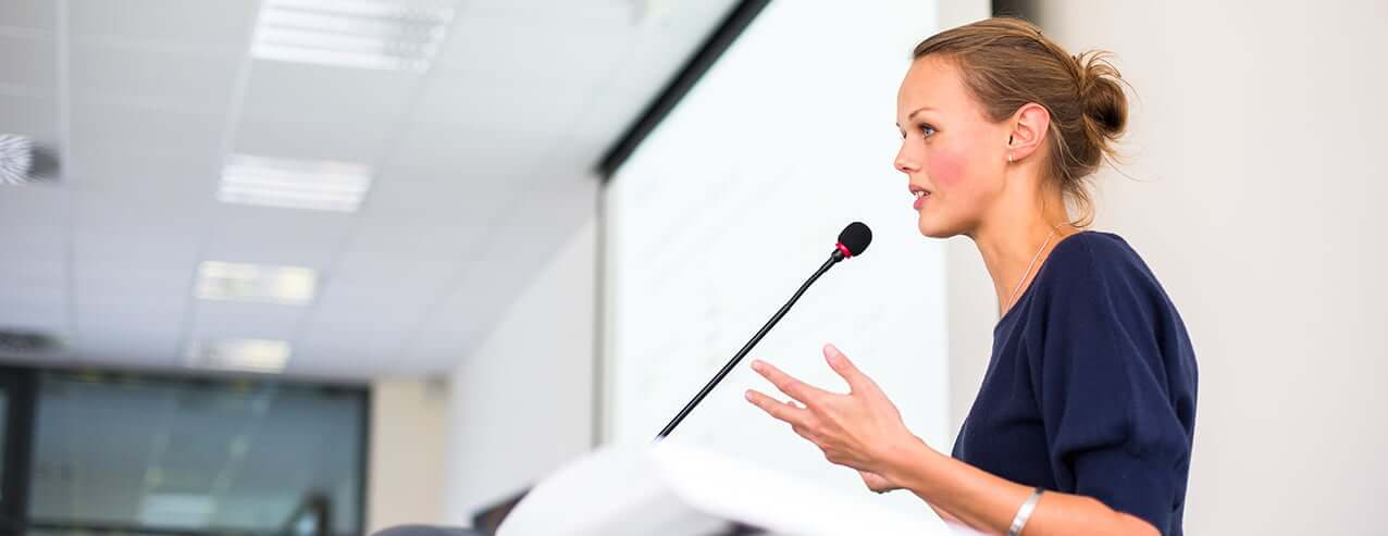 Educational leader speaking into microphone at podium