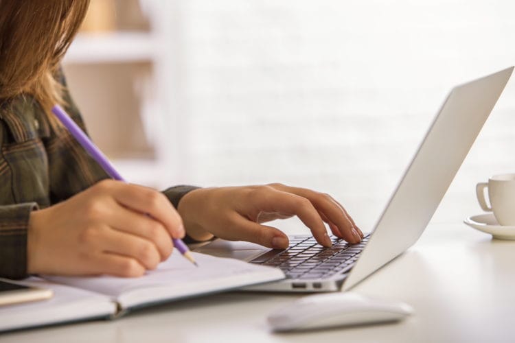 Person typing on laptop keyboard at desk