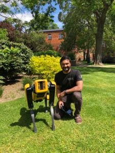 Harin Sellahewa crouched with robot dog