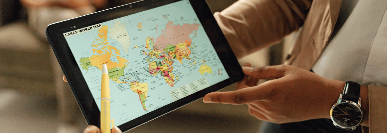 Human hands holding digital tablet displaying world map
