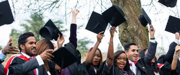 Students throwing graduation caps in air