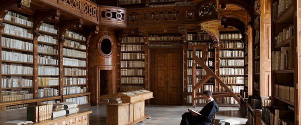 Man sitting in large historic library, reading