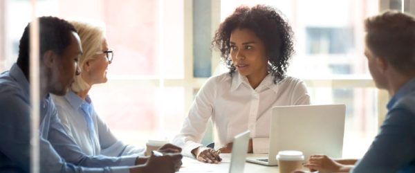 Four people sitting around office desk during meeting in professional office setting