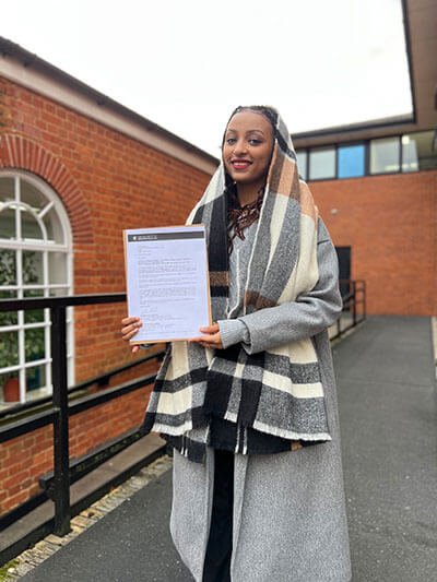 Hania Suliman at the University campus, holding confirmation of her scholarship