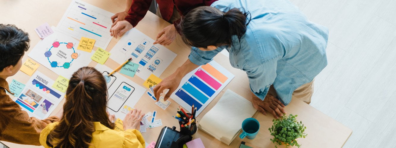 Group of four people gathered around desk with colourful marketing material