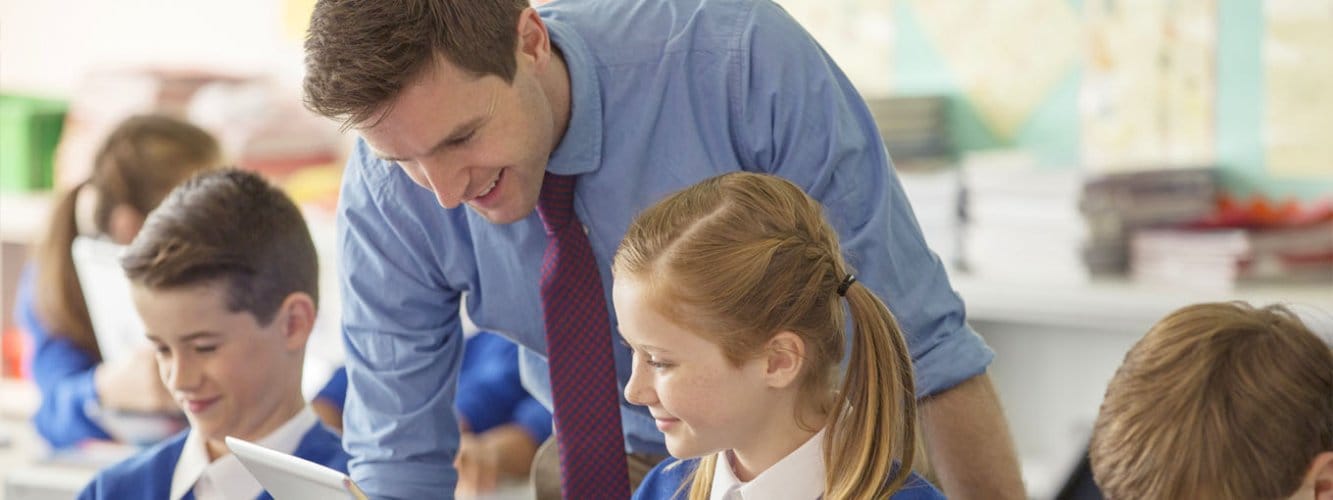 Teacher speaking to two primary school pupils in classroom