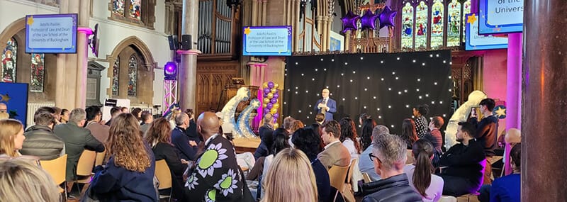 Law without Walls in the church, with balloons and screens advertising the event, and Adolfo speaking on stage
