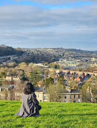 Rashmi looking out to city view in Bath from hilltop