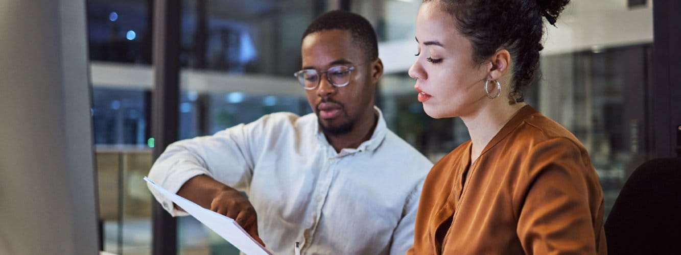 Male and female legal colleagues reviewing document at desk together, modern office setting