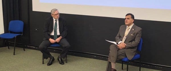 Professor Julian Richards and Mr Faisal speaking on stage at The University of Buckingham