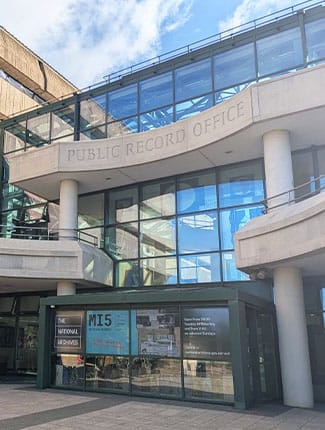 Grand building with a mix of old and modern architecture. Stone engraved with 'Public Record Office' with modern National Archives entrance below.