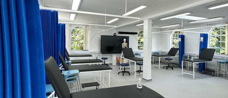 Medical school room, with medical beds and curtains, screen and skeleton at the back of the room