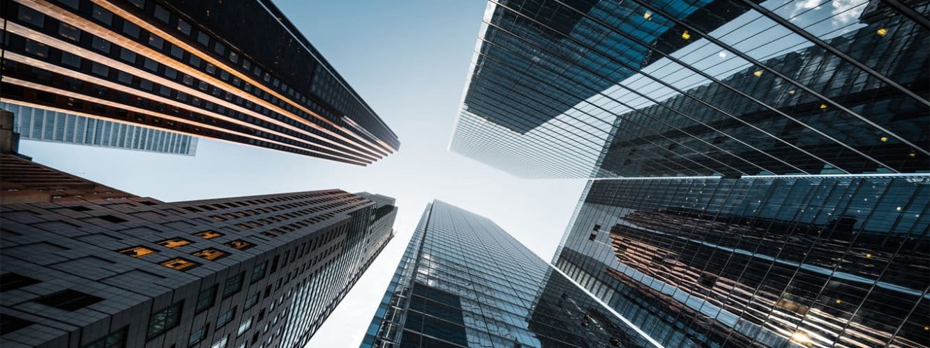 Ground-level view looking up to sky, surrounded by skyscrapers in modern city