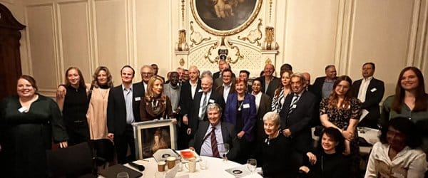 Group of people gathered around round table in stately room