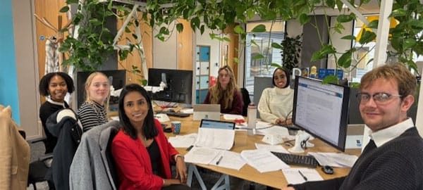 Law students around desk at law firm for work experience
