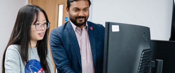 Professor Harin Sellahewa helping female student at computer