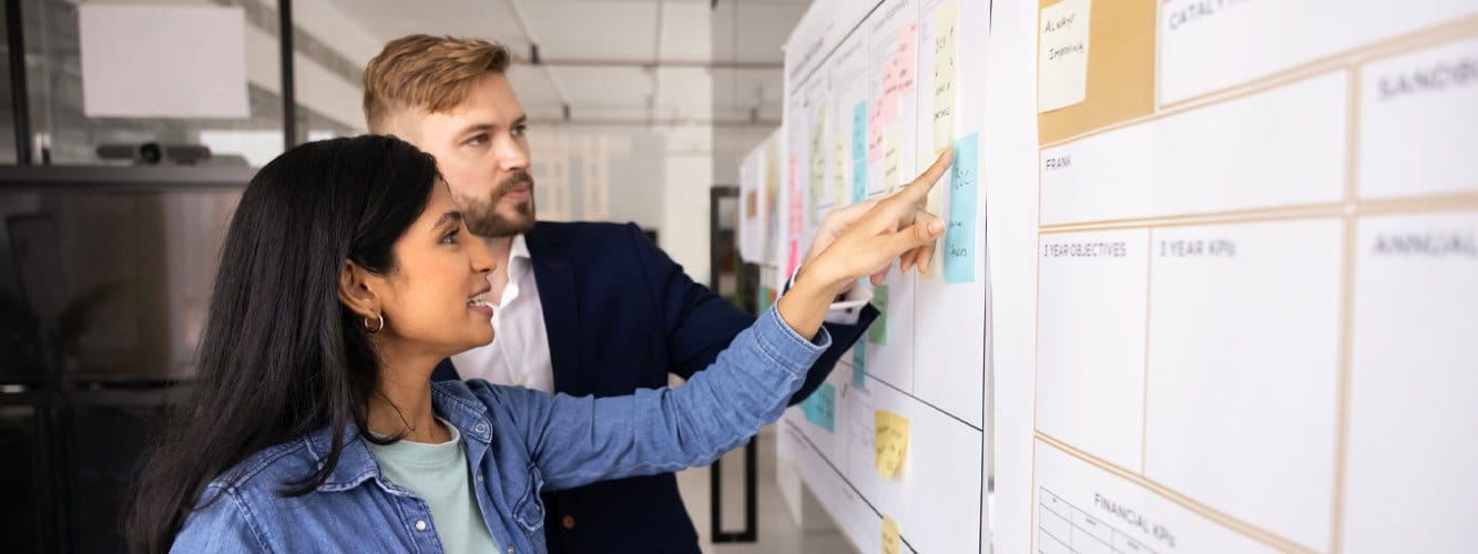 Male and female student working with post-its and plans on wall