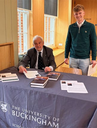 Michael Beloff KC signing books after the event, smiling with young attendee