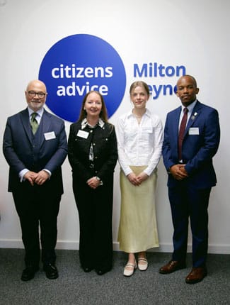 Staff and students from Buckingham standing in front of Citizens Advice Milton Keynes logo, at the offices